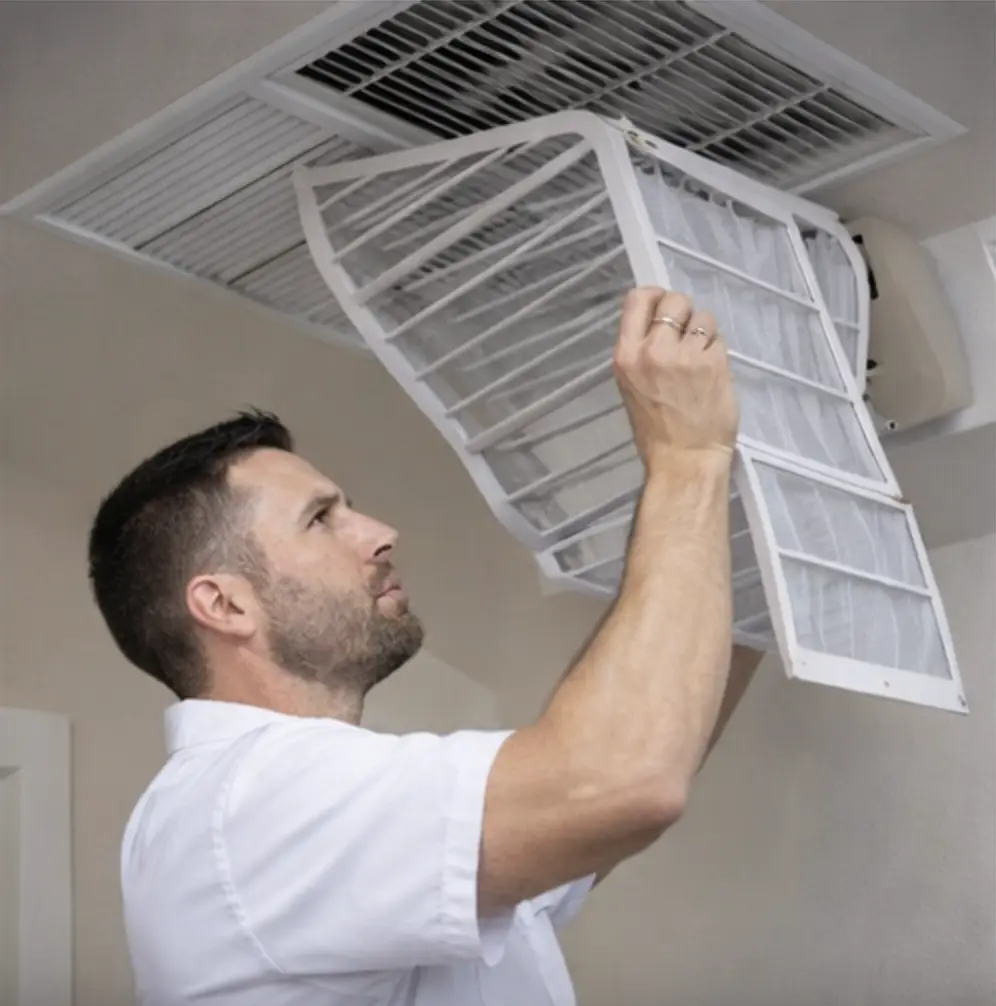 Green Air HVAC technician removing and inspecting an air filter during routine air conditioning maintenance